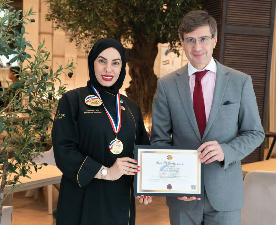 Chef Mariam Almansoori receiving her award certificate and medal from the French Ambassador to the UAE
