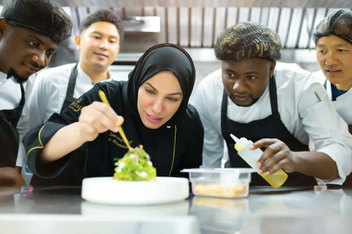 Chef Mariam Almansoori plating a dish with her kitchen brigade around her