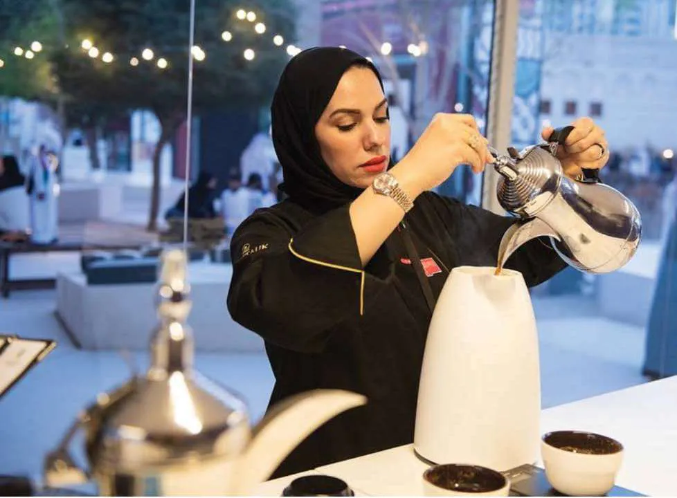 Chef Mariam pouring Arabic coffee at the ceremony table
